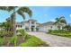 Stunning white home with a paver driveway, lush landscaping, and palm trees at 8537 Pavia Way, Bradenton, FL 34202