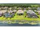 A serene backyard view showcasing the home, lawn, nearby lake, and neighboring residences at 8772 Stone Harbour Loop, Bradenton, FL 34212