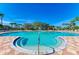 Large community pool surrounded by lounge chairs, mature landscaping, and clear blue skies at 8772 Stone Harbour Loop, Bradenton, FL 34212