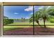 Enclosed patio featuring tropical palms, a serene lake view, and a refreshing breeze at 8772 Stone Harbour Loop, Bradenton, FL 34212