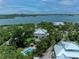 Stunning aerial view of a waterfront home with a pool, lush landscaping, and bay views at 8963 Fishermens Bay Dr, Sarasota, FL 34231