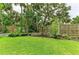 Well-maintained backyard featuring lush green grass, garden beds, and a charming wooden fence at 8963 Fishermens Bay Dr, Sarasota, FL 34231