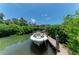 Boat at private dock surrounded by lush greenery and clear waterways, offering waterfront living at 8963 Fishermens Bay Dr, Sarasota, FL 34231