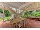 Covered patio with a brick floor, featuring an outdoor dining table and a view of the lush backyard at 8963 Fishermens Bay Dr, Sarasota, FL 34231