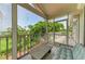Relax on this screened porch featuring a cozy bench, overlooking a verdant landscape and a bright blue sky at 8963 Fishermens Bay Dr, Sarasota, FL 34231