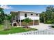 Exterior view of an elevated home surrounded by landscaping and a white picket fence at 105 Shore Rd, Nokomis, FL 34275