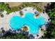 Aerial view of an uniquely-shaped community pool surrounded by lush greenery at 10611 Ladybug Cv, Parrish, FL 34219