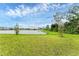 Lush green lawn stretches to a serene lake, framed by a clear sky at 10611 Ladybug Cv, Parrish, FL 34219