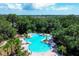 Aerial view of an uniquely-shaped community pool surrounded by lush greenery and lounge chairs at 10611 Ladybug Cv, Parrish, FL 34219