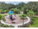 Community playground with a colorful playset, bench, and lush landscaping at 10611 Ladybug Cv, Parrish, FL 34219