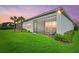 Green backyard features lush lawn with an exterior view of the home, and a twilight sky at 12139 Cranston Way, Bradenton, FL 34211