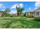 Beautifully landscaped backyard with lush green grass, mature trees, and flowering plants at 1605 Landfall Dr, Nokomis, FL 34275