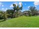 Well-manicured backyard featuring lush lawn, mature trees, and manicured landscaping at 1605 Landfall Dr, Nokomis, FL 34275