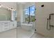 Modern bath features soaking tub, seamless glass shower, large window, and dual vanity with quartz countertops at 1605 Landfall Dr, Nokomis, FL 34275