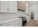 Modern kitchen features white cabinetry, stainless appliances, quartz counters, and decorative backsplash at 1605 Landfall Dr, Nokomis, FL 34275