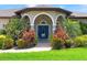 Arched entryway with vibrant blue door, flanked by lush, colorful landscaping at 1711 145Th E St, Sarasota, FL 34212
