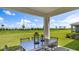 Covered back patio featuring an outdoor dining set overlooking a well-maintained lawn at 17904 Tavernside Trl, Bradenton, FL 34211