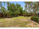 Landscaped backyard featuring a wood fence, green lawn, and mature tropical trees that provide a serene and private outdoor space at 3631 Palm Dr, Punta Gorda, FL 33950