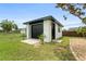 Detached garage with a black door and trim that is surrounded by a beautiful green lawn with a blue sky at 3631 Palm Dr, Punta Gorda, FL 33950