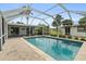 Sparkling pool with a screened-in enclosure, perfect for outdoor relaxation and entertaining, surrounded by a brick paver patio at 3631 Palm Dr, Punta Gorda, FL 33950