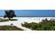 Beautiful beach view with white sand, blue water, volleyball net, and a clear blue sky at 3634 Torrey Pines Way Way, Sarasota, FL 34238