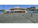 Well-maintained tennis court with a clubhouse in the background, surrounded by palm trees at 3634 Torrey Pines Way Way, Sarasota, FL 34238
