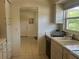 Neutral kitchen features dual sink, tiled floor, light cabinetry, and access to additional rooms at 4149 Prudence Dr, Sarasota, FL 34235