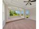 Carpeted bedroom featuring a tray ceiling, ceiling fan, and a door leading to outdoor views at 4307 70Th E Ave, Ellenton, FL 34222