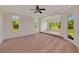Spacious carpeted bedroom with tray ceilings, ceiling fan, and natural light from surrounding windows at 4307 70Th E Ave, Ellenton, FL 34222