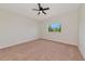 A carpeted bedroom features a ceiling fan and a window overlooking lush green trees at 4307 70Th E Ave, Ellenton, FL 34222
