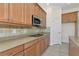 Close-up of kitchen counter with granite counters, tile backsplash and stainless microwave at 4307 70Th E Ave, Ellenton, FL 34222