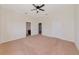 Spacious carpeted bedroom with ceiling fan, view to ensuite bathroom, and entry door to hall at 4307 70Th E Ave, Ellenton, FL 34222
