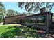 Home's backyard featuring lush green lawn, mature trees, and a cozy sunroom addition at 4555 Chandlers Forde # 47, Sarasota, FL 34235