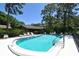 Community pool surrounded by mature trees and lounge chairs for relaxation at 4555 Chandlers Forde # 47, Sarasota, FL 34235