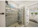 Elegant bathroom featuring frameless shower with tiled walls, niche, bench and a view of the lake and main bedroom at 460 Daylily Blvd, Nokomis, FL 34275
