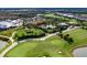 Aerial view of a lush golf course, tennis courts, community pool, and elegant homes in a planned community at 4949 Savona Run, Bradenton, FL 34211