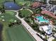 Aerial view showcasing the golf course, community pool, clubhouse, and homes in a vibrant community at 4949 Savona Run, Bradenton, FL 34211