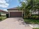 Charming home featuring a well-manicured front lawn, brown garage door and a brick driveway at 4949 Savona Run, Bradenton, FL 34211