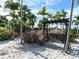 Tranquil hammock swing on a sandy beach surrounded by palm trees and lush greenery at 4949 Savona Run, Bradenton, FL 34211