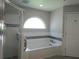 Bright bathroom featuring a tub with a large arched window and tiled walls at 5207 86Th Street W Ct, Bradenton, FL 34210