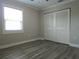 This bedroom has gray wood floors, a window with blinds, and a closet with louvered doors at 5207 86Th Street W Ct, Bradenton, FL 34210