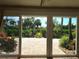 A view of the exterior patio surrounded by beautiful greenery seen through large sliding glass doors at 5207 86Th Street W Ct, Bradenton, FL 34210
