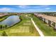 An aerial view shows a golf course community with condos and meticulously maintained green spaces near a serene lake at 5695 Palmer Cir # 203, Bradenton, FL 34211