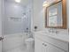 Bright bathroom featuring a tub with glass enclosure and a vanity with a framed mirror at 5866 Cavano Dr, Sarasota, FL 34231