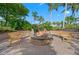 Cozy outdoor fire pit with seating, surrounded by tropical landscaping and a beautiful blue sky at 5866 Cavano Dr, Sarasota, FL 34231