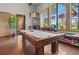 Spacious game room with a pool table and large windows overlooking a beautiful garden at 5866 Cavano Dr, Sarasota, FL 34231