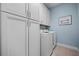 Neat laundry room with white cabinets and a modern washer and dryer at 5866 Cavano Dr, Sarasota, FL 34231