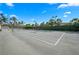 Lit outdoor tennis court showcasing well-maintained surface, palm trees, and blue sky at 5866 Cavano Dr, Sarasota, FL 34231