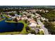 Scenic aerial view of a community with pond, mature trees and tile roofs at 5897 Carriage Dr, Sarasota, FL 34243