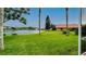 Expansive backyard with a serene pond view, featuring lush grass and palm trees at 5897 Carriage Dr, Sarasota, FL 34243